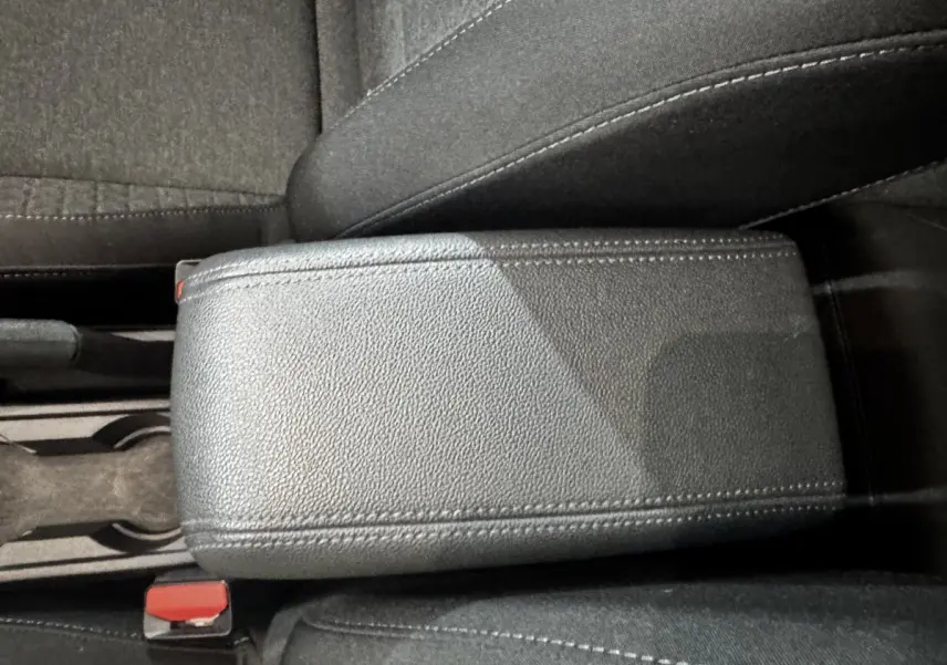 Gros plan sur l'accoudoir central en cuir synthétique gris foncé de la Renault Clio Business TCe 100, intérieur tissu noir.