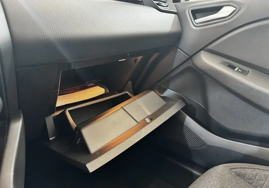 Vue intérieure côté passager de la Renault Clio Business 2020, boîte à gants ouverte avec documents visibles, finition noire.