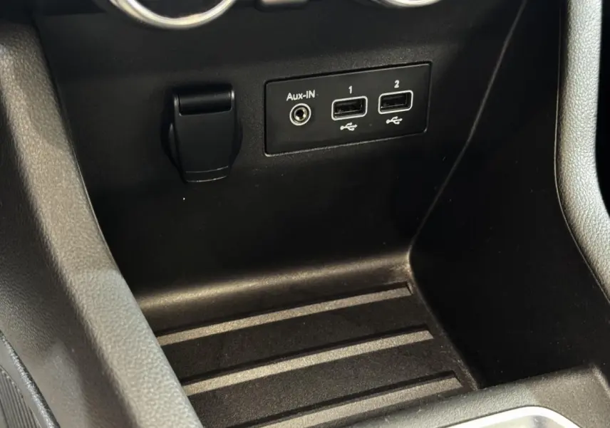 Gros plan sur la console centrale noire de la Renault Clio Business TCe 100 avec ports USB et prise Aux-In.