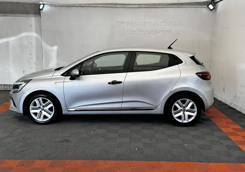 Profil droit d'une Renault Clio Business TCe 100 gris clair 2020, avec jantes alliage et poignées noires, dans un garage.