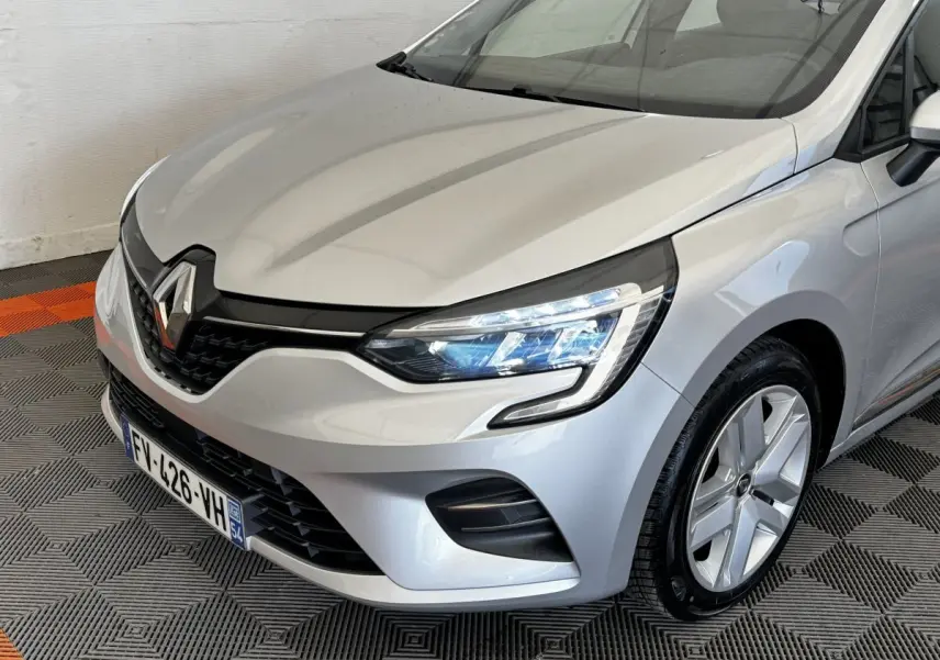 Vue 3/4 avant droit d'une Renault Clio Business TCe 100 gris clair avec phares LED et jantes alliage.