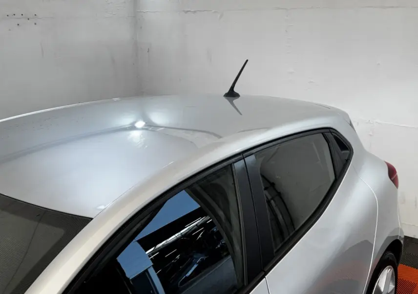 Vue 3/4 arrière droite d'une Renault Clio Business gris clair avec vitres teintées et antenne de toit noire.