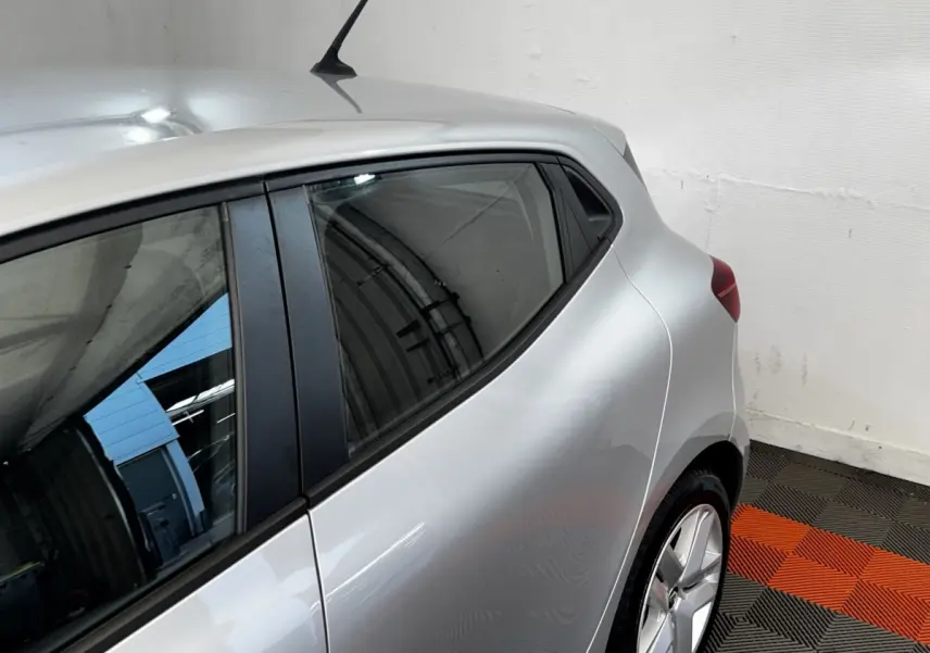 Vue côté gauche arrière d'une Renault Clio Business gris clair, avec vitres teintées et jantes alliage visibles.