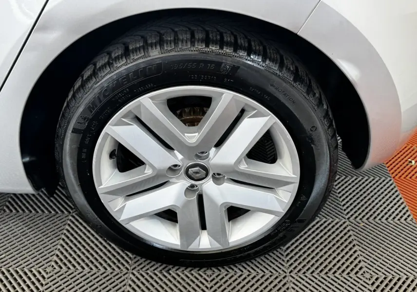 Gros plan sur la roue avant droite gris clair d'une Renault Clio Business TCe 100 avec jante en alliage et logo Renault central.