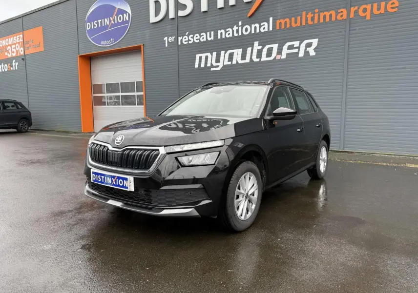 Vue 3/4 avant d'un Skoda Kamiq noir magic nacré avec calandre chromée et jantes argentées sur parking humide.