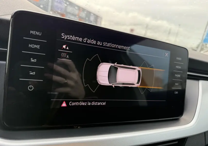 Écran tactile intérieur du Skoda Kamiq 2023 montrant l'aide au stationnement avec alertes de distance.