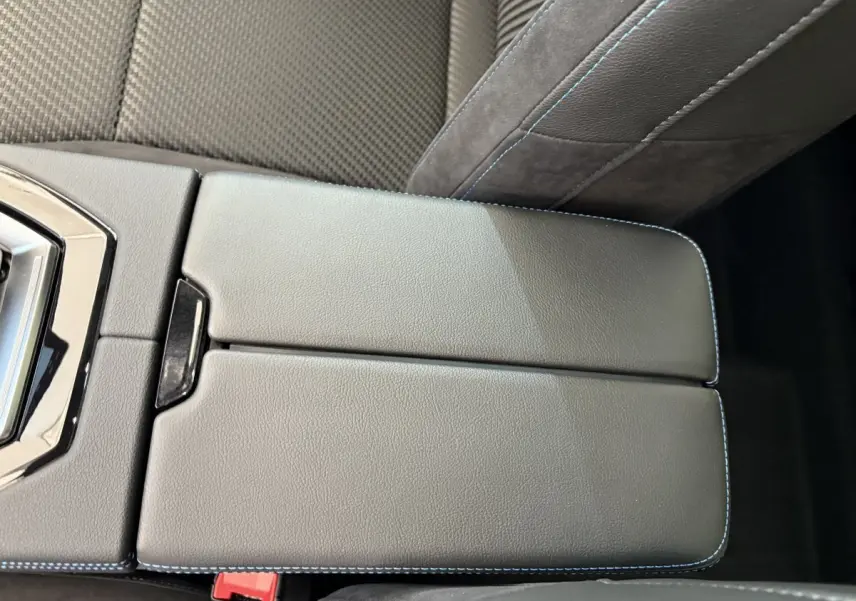 Gros plan sur l'accoudoir central en cuir gris avec surpiqûres bleues dans l'habitacle du Renault Espace blanc.