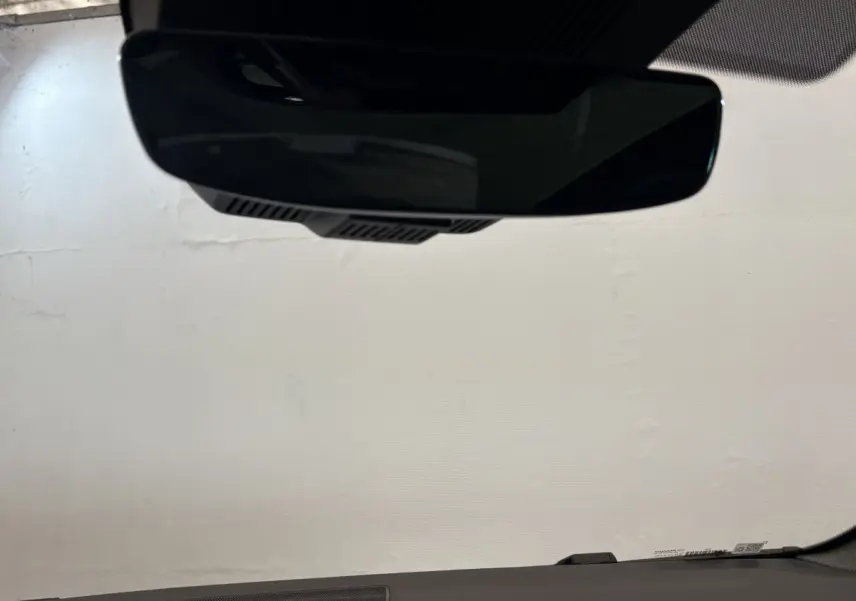 Vue intérieure du rétroviseur central d'un Renault Espace blanc 2025, avec tableau de bord sombre en arrière-plan.