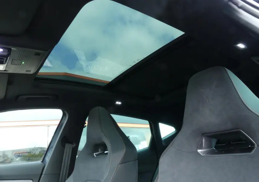 Vue intérieure du toit ouvrant panoramique et des sièges baquets suédine noirs avec surpiqûres cuivrées du Cupra Formentor.