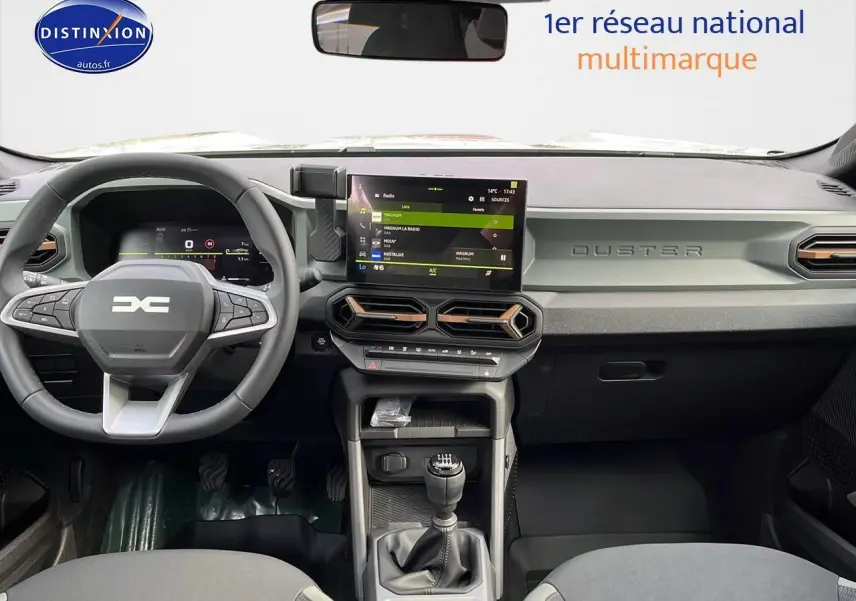 Intérieur moderne du Dacia Duster 2025, vue frontale sur tableau de bord gris avec écran tactile et boîte manuelle.