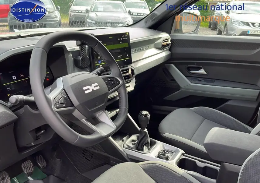 Intérieur du Dacia Duster 2025 essence, vue côté conducteur, volant multifonction et console centrale avec boîte manuelle.