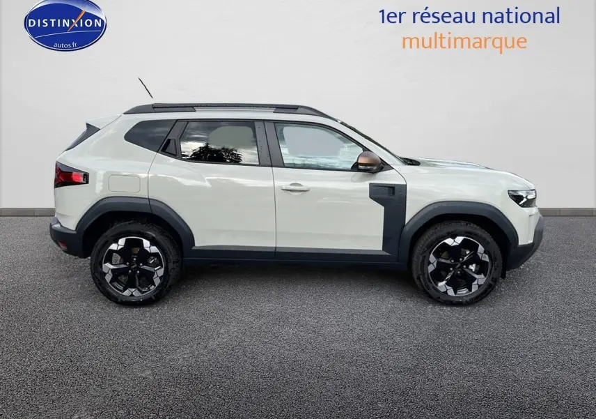 Profil droit du Dacia Duster 2025 couleur Sandstone avec barres de toit et jantes alu noires.