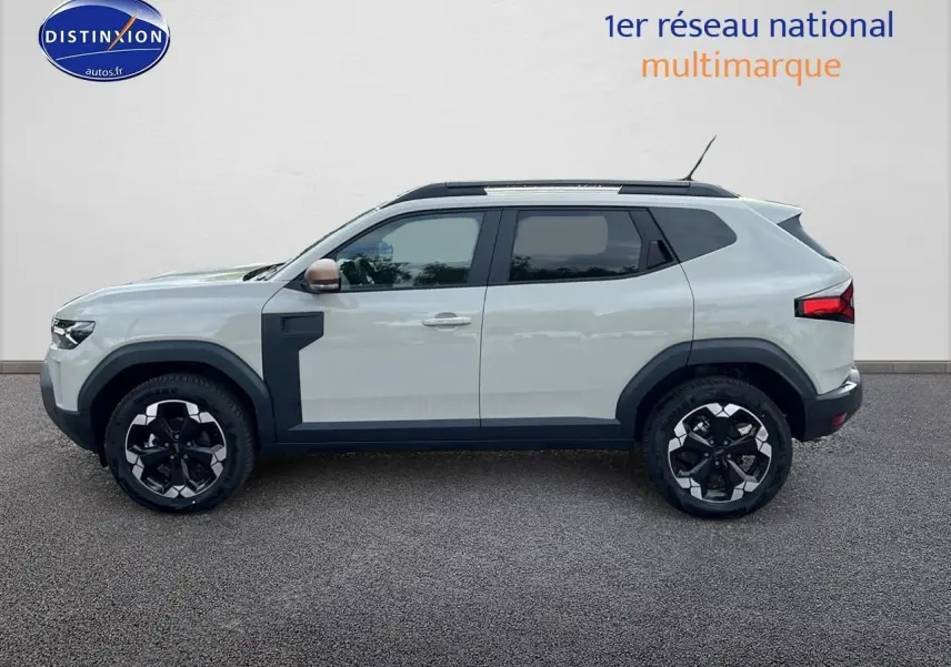 Profil côté gauche du Dacia Duster 2025 couleur Sandstone avec jantes alu et barres de toit noires.
