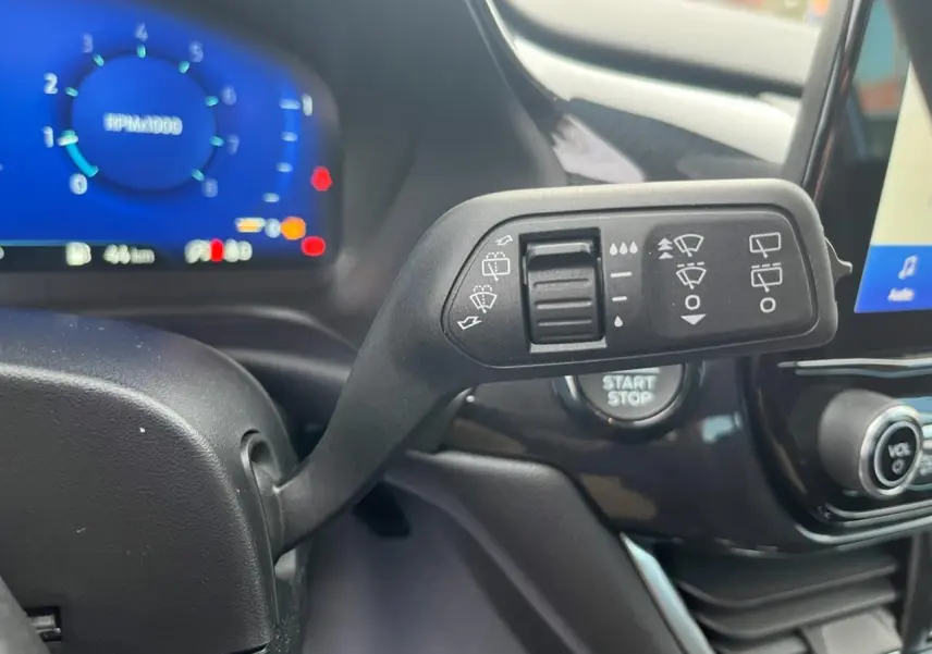 Gros plan sur la commande d'essuie-glace du Ford Puma 2022, avec tableau de bord numérique bleu en arrière-plan.