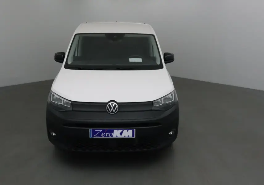 Vue frontale d'un Volkswagen Caddy Maxi blanc avec pare-chocs noir mat et plaque "Zero KM" visible.