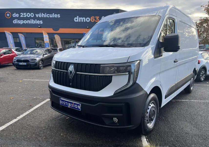 Renault Master blanc en 3/4 avant droit, avec calandre noire verticale et pare-chocs noir mat, stationné en extérieur.