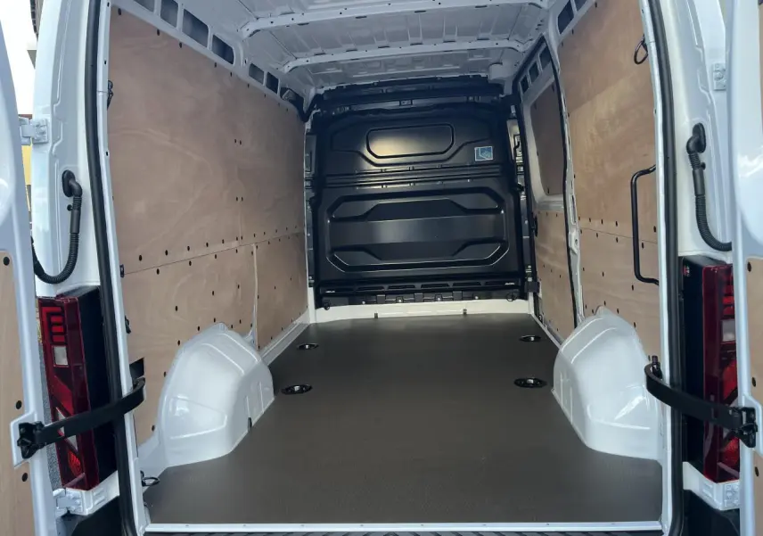 Vue arrière intérieure du Renault Master blanc 2025, montrant l'espace de chargement avec plancher bois et parois latérales tôlées.