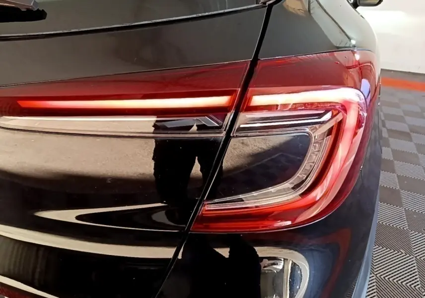 Gros plan sur le feu arrière droit rouge et blanc du Renault Captur Business noir de 2021, avec reflet sur la carrosserie.