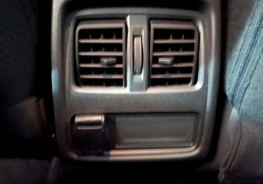 Gros plan sur la sortie d’air arrière et prise 12V du Renault Captur Business noir, intérieur sombre.