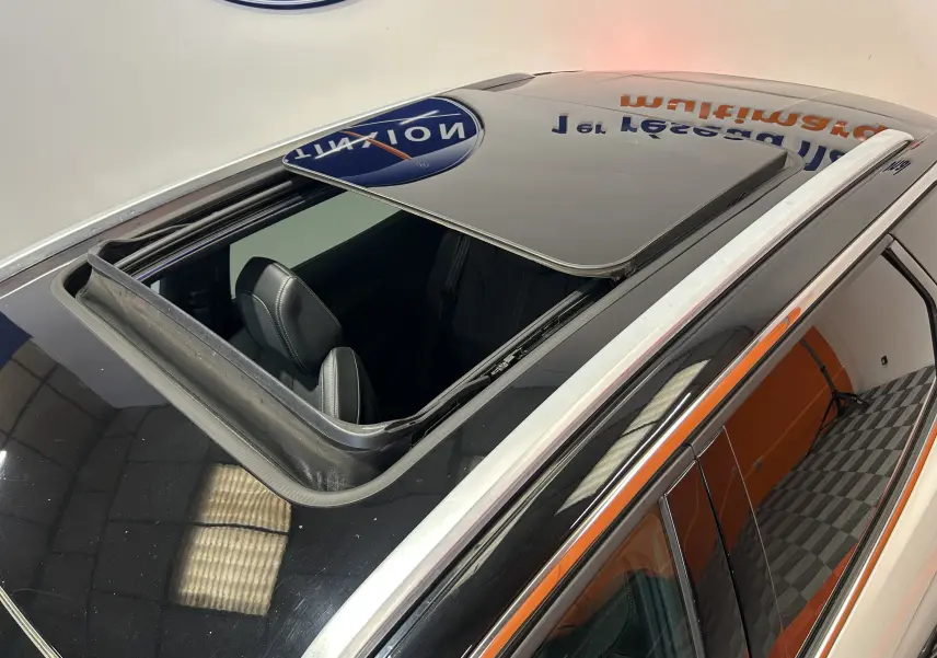 Toit ouvrant ouvert vu en plongée sur le toit noir du Peugeot 3008 blanc, avec intérieur cuir visible côté conducteur.