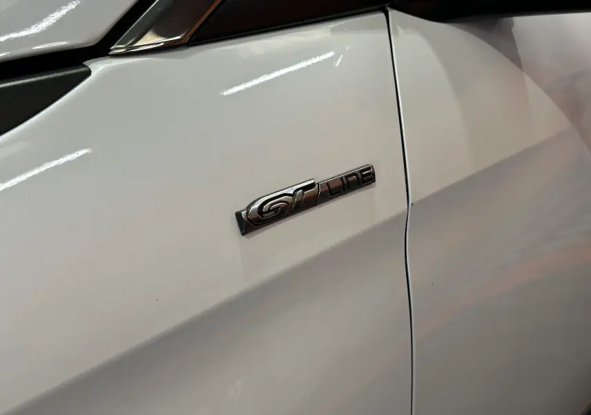 Gros plan sur l’emblème GT Line sur la porte blanche côté gauche du Peugeot 3008, finition sportive visible.