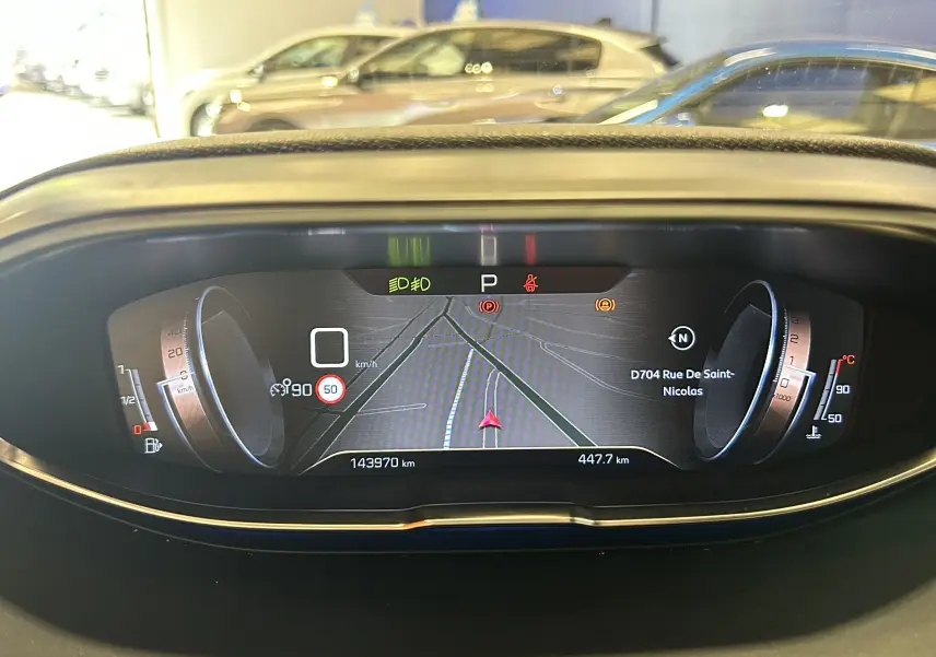 Tableau de bord numérique du Peugeot 3008 blanc, affichant la navigation et les indicateurs de vitesse et température.