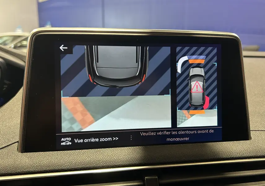 Écran de la caméra de recul du Peugeot 3008 blanc, vue arrière avec alertes de proximité en couleur.