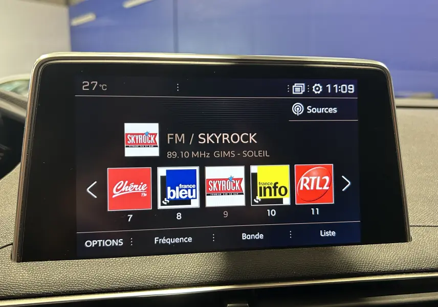 Écran central du tableau de bord d’un Peugeot 3008 blanc, affichant la radio FM sur Skyrock à 11h09.