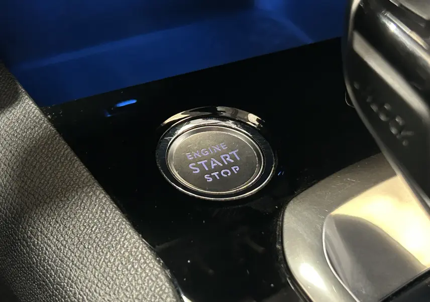 Gros plan sur le bouton start/stop moteur dans l'habitacle noir brillant du Peugeot 3008 blanc GT Line 2020.