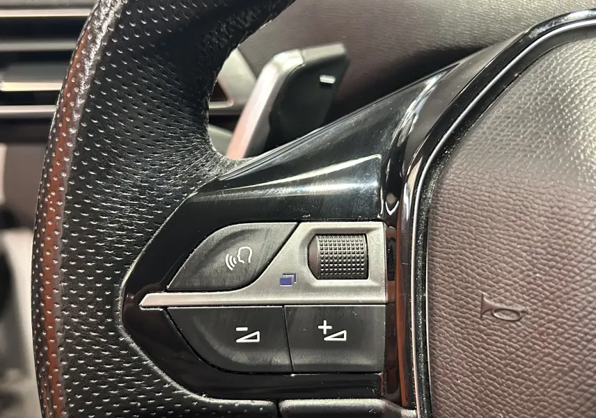 Gros plan sur les commandes noires du volant en cuir perforé du Peugeot 3008 blanc, version GT Line 2020.