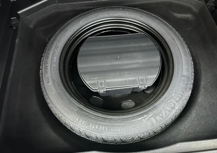 Gros plan sur la roue de secours noire logée dans le coffre d’un Peugeot 3008 blanc, version GT Line.