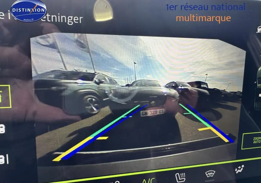 Vue caméra de recul montrant plusieurs véhicules stationnés dont un Dacia Duster vert cèdre à gauche.