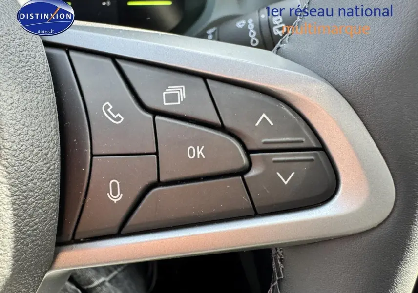 Gros plan sur les commandes multifonctions noires du volant du Dacia Duster 2025, finition Expression, intérieur gris.