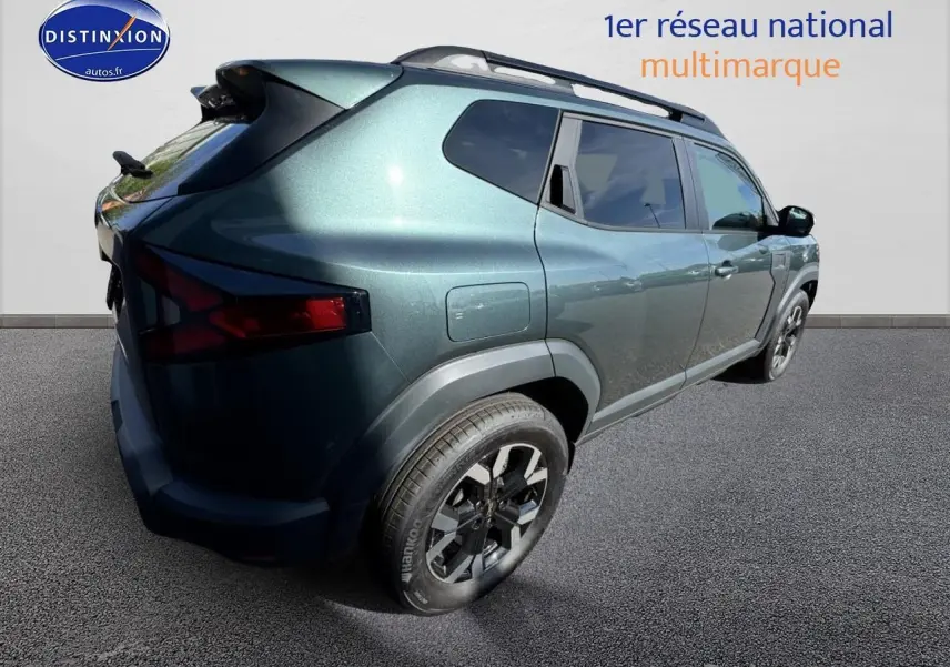 Vue 3/4 arrière droite du Dacia Duster 2025 vert cèdre avec jantes alu et barres de toit visibles.