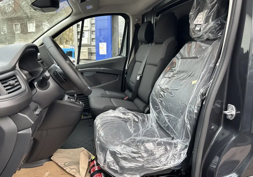Vue intérieure côté conducteur du Renault Trafic Fourgon gris Comète 2025, siège passager protégé par housse plastique.