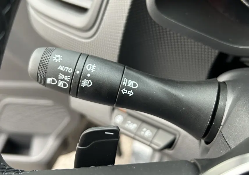 Gros plan sur la commande des feux et clignotants à gauche du volant du Renault Trafic Fourgon gris Comète.