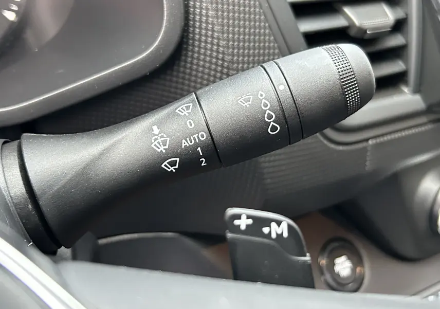 Gros plan sur la commande d’essuie-glace du Renault Trafic Fourgon gris, avec palettes de changement de vitesse visibles.