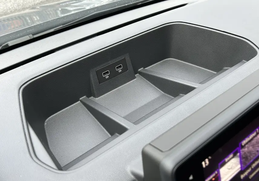 Gros plan sur le rangement central du tableau de bord du Renault Trafic Fourgon gris, avec deux ports USB visibles.