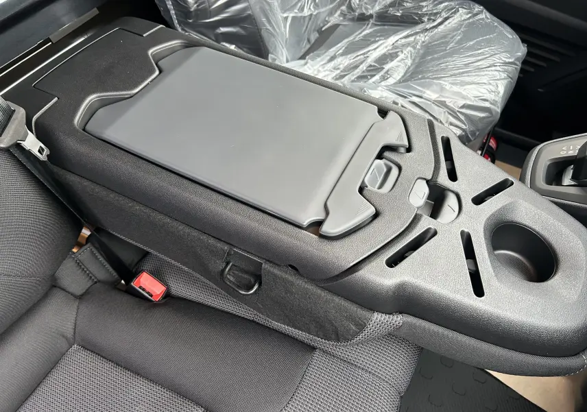 Vue rapprochée de la console centrale noire et des sièges tissu gris à l'intérieur du Renault Trafic Fourgon 2025.