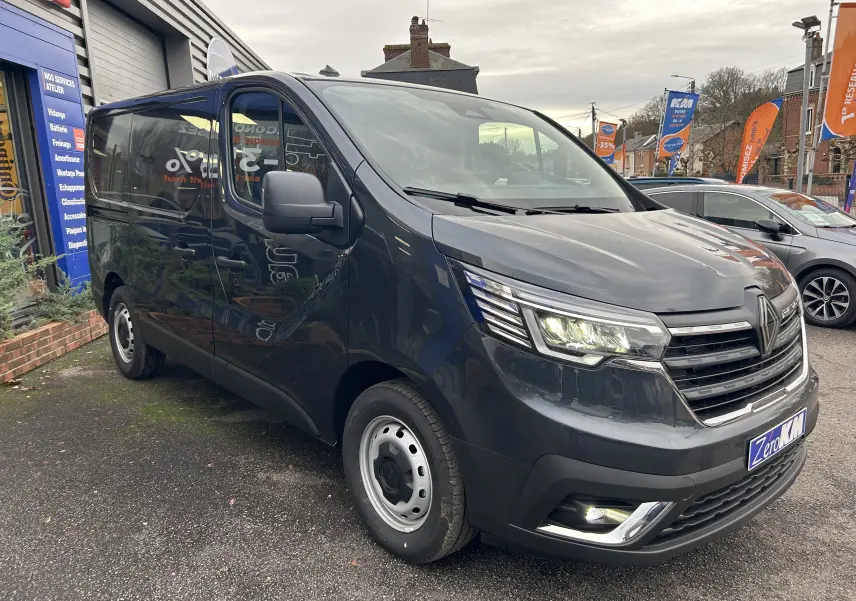 Renault Trafic Fourgon gris Comète en 3/4 avant droit, avec phares LED allumés et jantes acier simples.