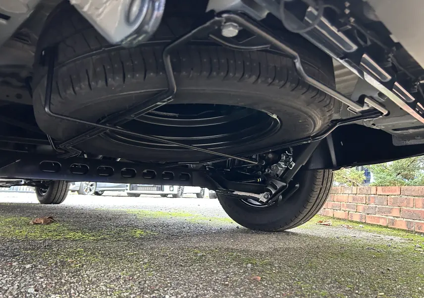 Vue en contre-plongée sous le Renault Trafic Fourgon gris, montrant la roue de secours et le châssis arrière.
