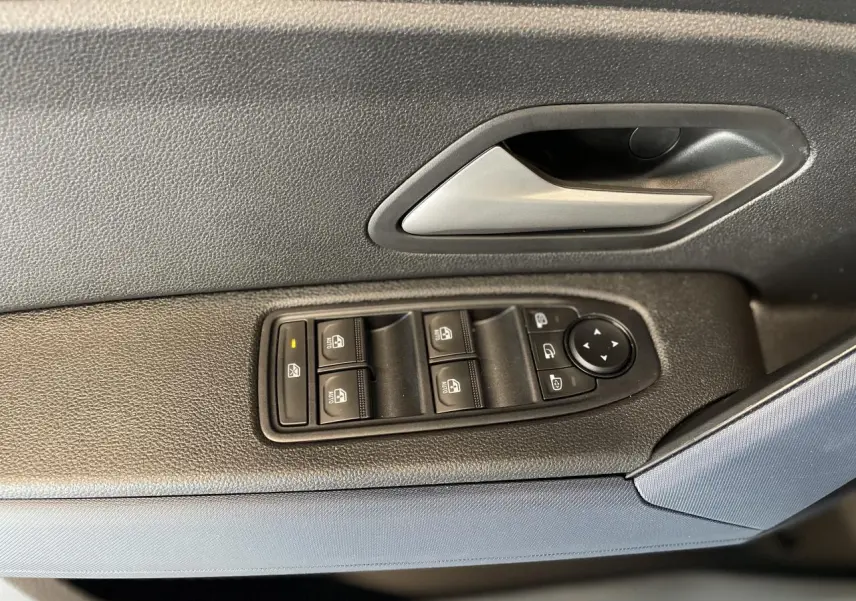 Gros plan sur la commande des vitres électriques côté conducteur d'un Dacia Duster beige avec poignée intérieure grise.