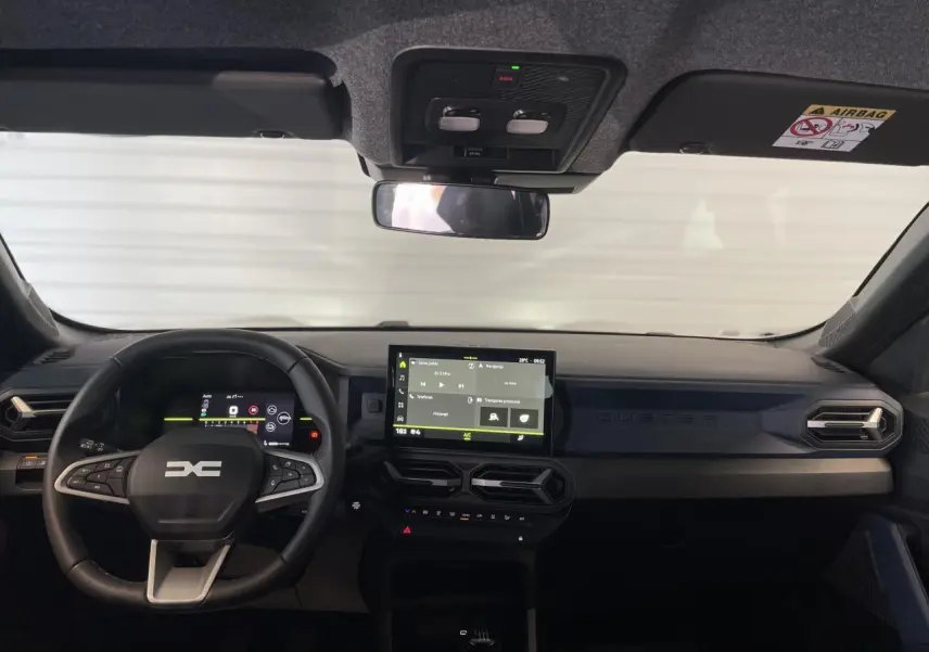 Vue frontale de l’habitacle du Dacia Duster beige 2025, avec tableau de bord digital et écran tactile central.