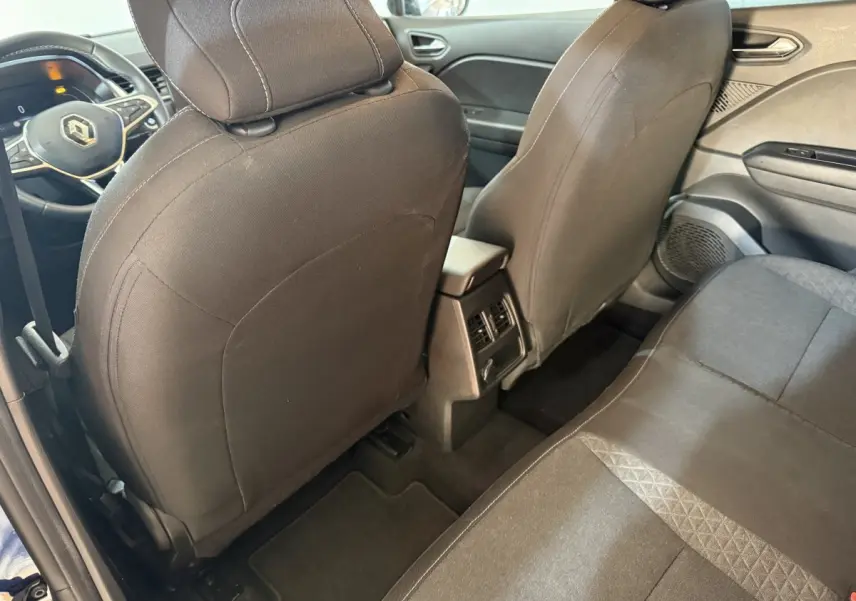 Vue intérieure arrière du Renault Captur 2024, sièges noirs et console centrale avec aérateurs visibles.