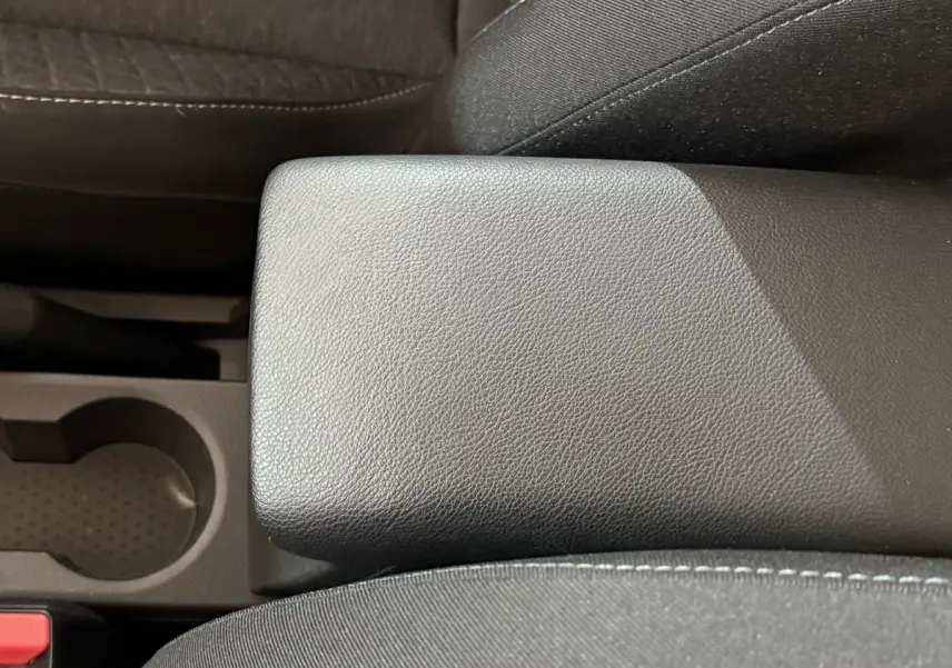 Gros plan sur l'accoudoir central en cuir synthétique noir et porte-gobelet du Renault Captur 2024.