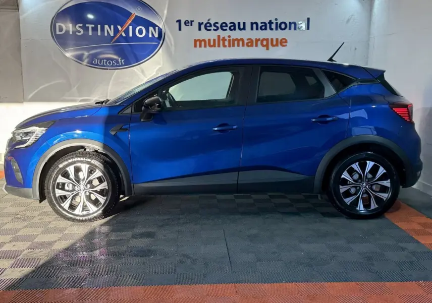 Profil gauche d'un Renault Captur bleu 2024 avec jantes alliage et protections noires sur les passages de roues.