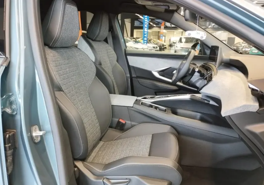 Vue intérieure côté gauche du Peugeot 3008 Bleu Azur 2025, sièges tissu gris et cuir noir avec tableau de bord moderne.