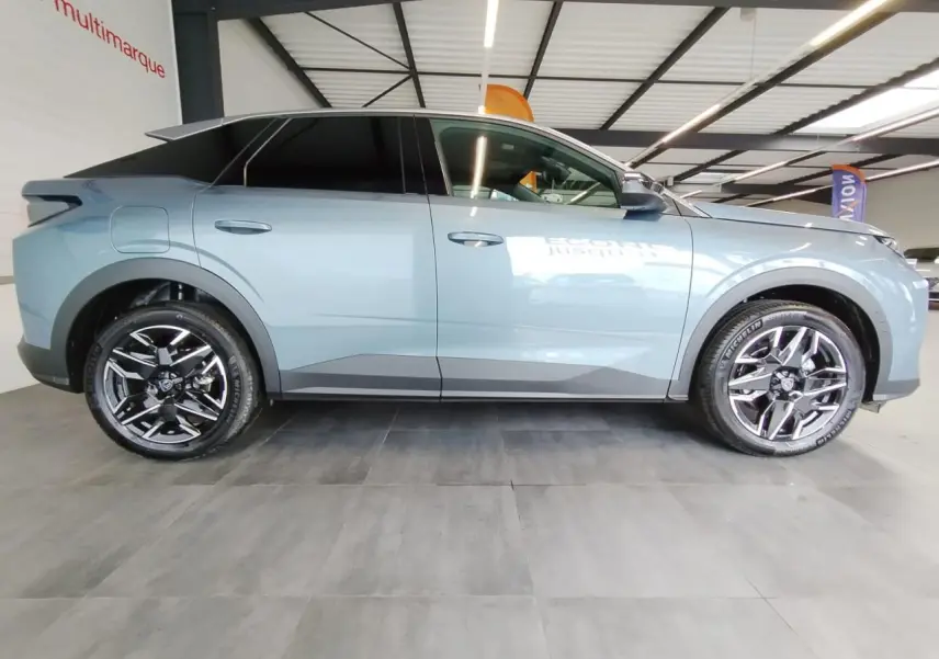 Profil côté gauche du Peugeot 3008 hybride 2025 en bleu métallisé avec jantes alliage noires diamantées.