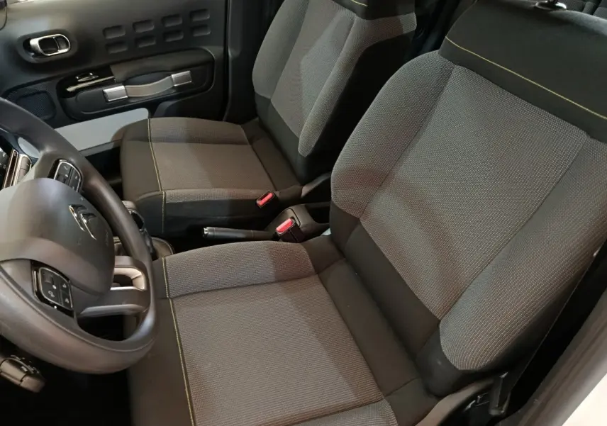 Vue intérieure côté conducteur de la Citroën C3 2020, sièges tissu gris avec surpiqûres jaunes et volant multifonction.