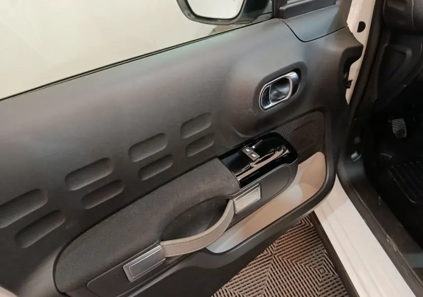 Vue rapprochée de la porte avant gauche blanche d’une Citroën C3 2020 avec commandes de vitres et poignée intégrée.